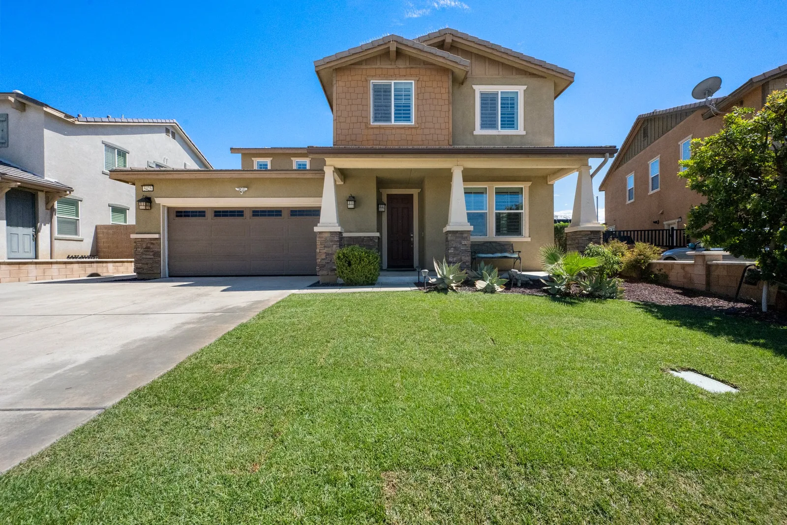 Two-story craftsman-style home with stone accents behind a green front lawn