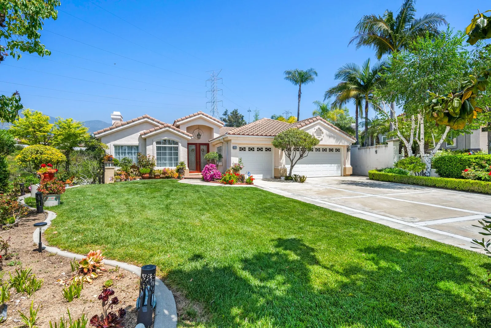 Tile-roofed home with a landscaped front yard framed by palm trees