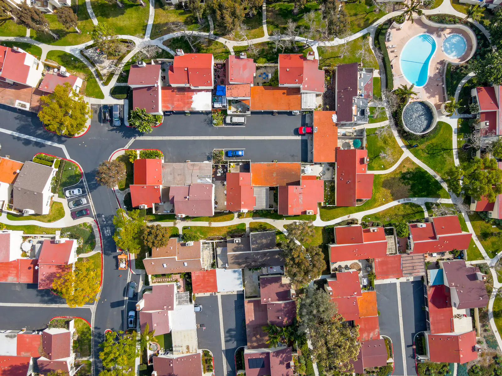 Aerial view looking straight down on red tile roofs, curving walkways and a community pool