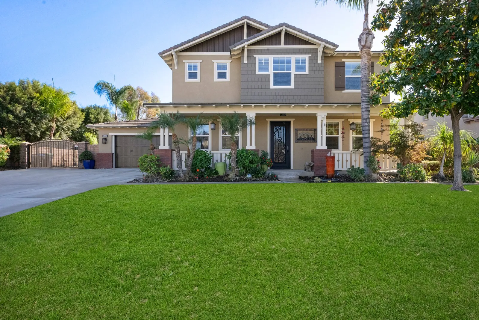 Two-story craftsman-style home with a wraparound porch behind a wide lawn